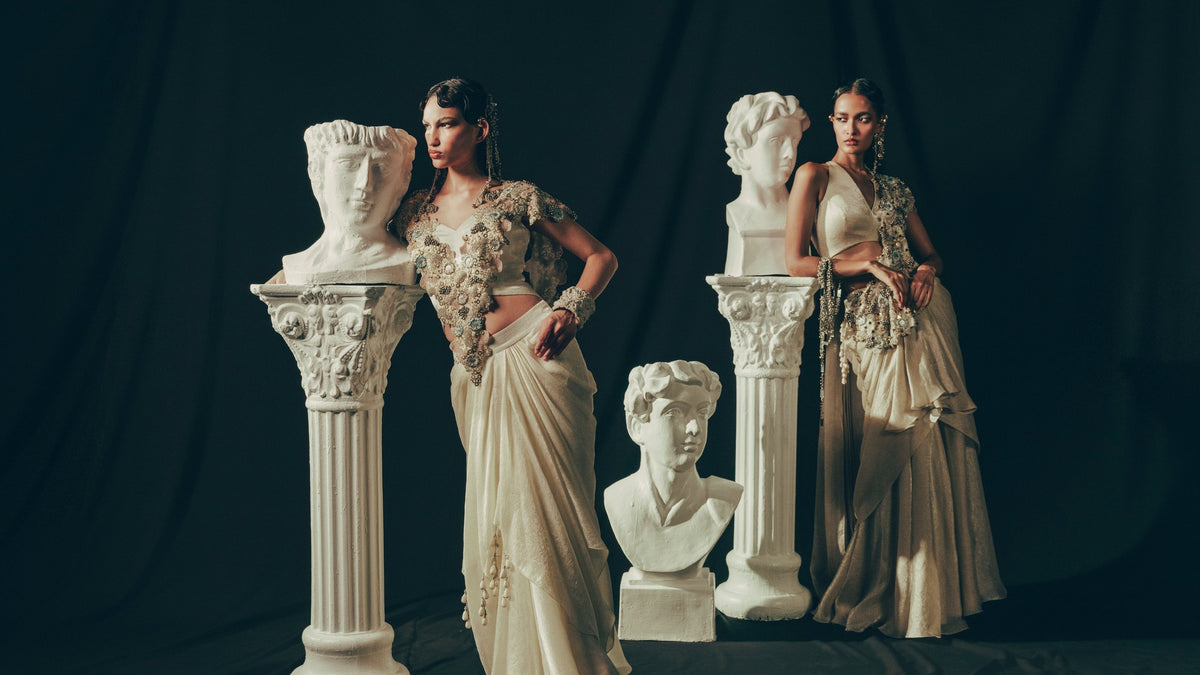 Two models in ivory hand-embroidered drapes with plaster busts and columns