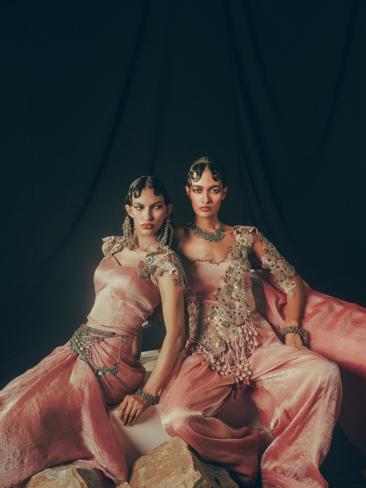 Two models seated in blush pink hand-embroidered sets